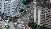 Pemandangan udara ini, menunjukkan tim penyelamat dan pencarian berada di lokasi runtuhnya sebagian menara apartemen tepi laut di Surfside, utara Miami, Kamis (24/6/2021). Tim tanggap menggunakan anjing dan drone terlatih untuk mencari korban selamat. (CHANDAN KHANNA/AFP)