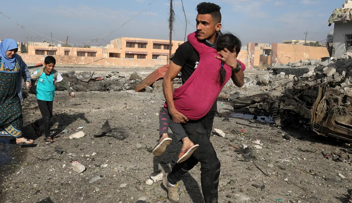 Tentara pasukan khusus Irak berjalan sambil menggendong seorang gadis yang terluka menyusul serangan bom mobil bunuh diri yang dilakukan militan ISIS di kota Tahrir, Irak, 17 November 2016. (REUTERS/Goran Tomasevic)