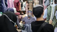 Pedagang menggunakan alat pelindung wajah (Face Shield) saat melayani pembeli di Kawasan Tanah Abang, Jakarta, Senin (18/5/2020). Penggunaan alat pelindung wajah itu sebagai upaya untuk melindungi diri saat berhubungan dengan pembeli dalam pecegahan penyebaran COVID-19. (Liputan6.com/Faizal Fanani)