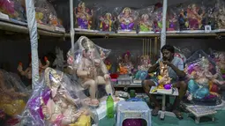 Perajin mengerjakan patung dewa Hindu berkepala gajah Lord Ganesha di sebuah lokakarya menjelang festival Ganesh Chaturthi di Mumbai (12/8/2021). Festival Ganesh Chaturthi adalah perayaan kelahiran Ganesha, dewa kebijaksanaan, kemakmuran, dan keberuntungan Hindu. (AFP/Punit Paranjpe)