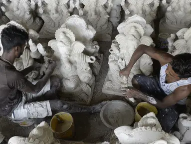Para perajin menyelesaikan pembuatan patung Dewa Ganesha di sebuah bengkel di pinggiran Hyderabad, India, Senin (29/6/2020). Patung Dewa Ganesha banyak ditemukan di berbagai penjuru India termasuk Nepal, Tibet, dan Asia Tenggara. (NOAH SEELAM/AFP)