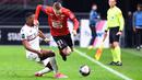 Bek Rennes, Adrien Truffert (kanan) berebut bola dengan striker Nice, Myziane Maolida dalam laga lanjutan Liga Prancis 2020/21 pekan ke-27 di Roazhon Park Stadium, Rennes, Jumat, (26/2/2021). Rennes kalah 1-2 dari Nice. (AFP/Damien Meyer)