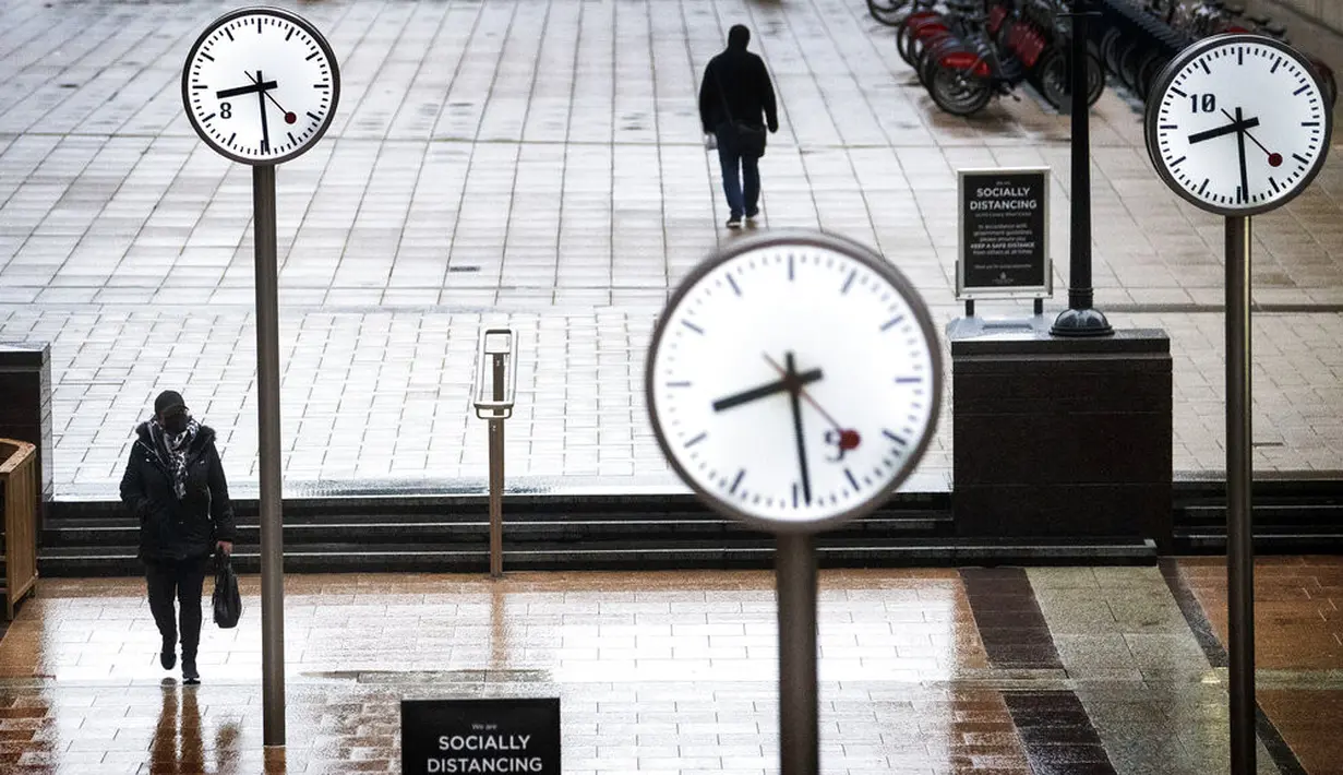 Para penumpang berjalan melalui Canary Wharf yang hampir sepi selama jam sibuk di London, Inggris, 12 Januari 2021. Inggris sedang menerapkan lockdown nasional ketiga untuk mengekang penyebaran virus corona COVID-19. (Victoria Jones/PA via AP)