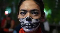 Seorang wanita melukis wajahnya saat pesta Halloween di sebuah kafe di Tangerang (31/10/2021). (AFP/Adek Berry)