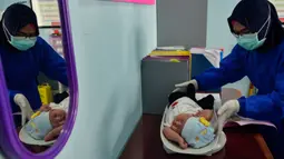 Petugas kesehatan menimbang berat badan bayi sebelum melakukan imunisasi di sebuah Pukesmas di Banda Aceh, Aceh, Senin (15/6/2020). Memasuki tatanan normal baru, pelayanan imunisasi anak kembali dibuka setelah sebelumnya sempat terhenti akibat pandemi COVID-19. (CHAIDEER MAHYUDDIN/AFP)