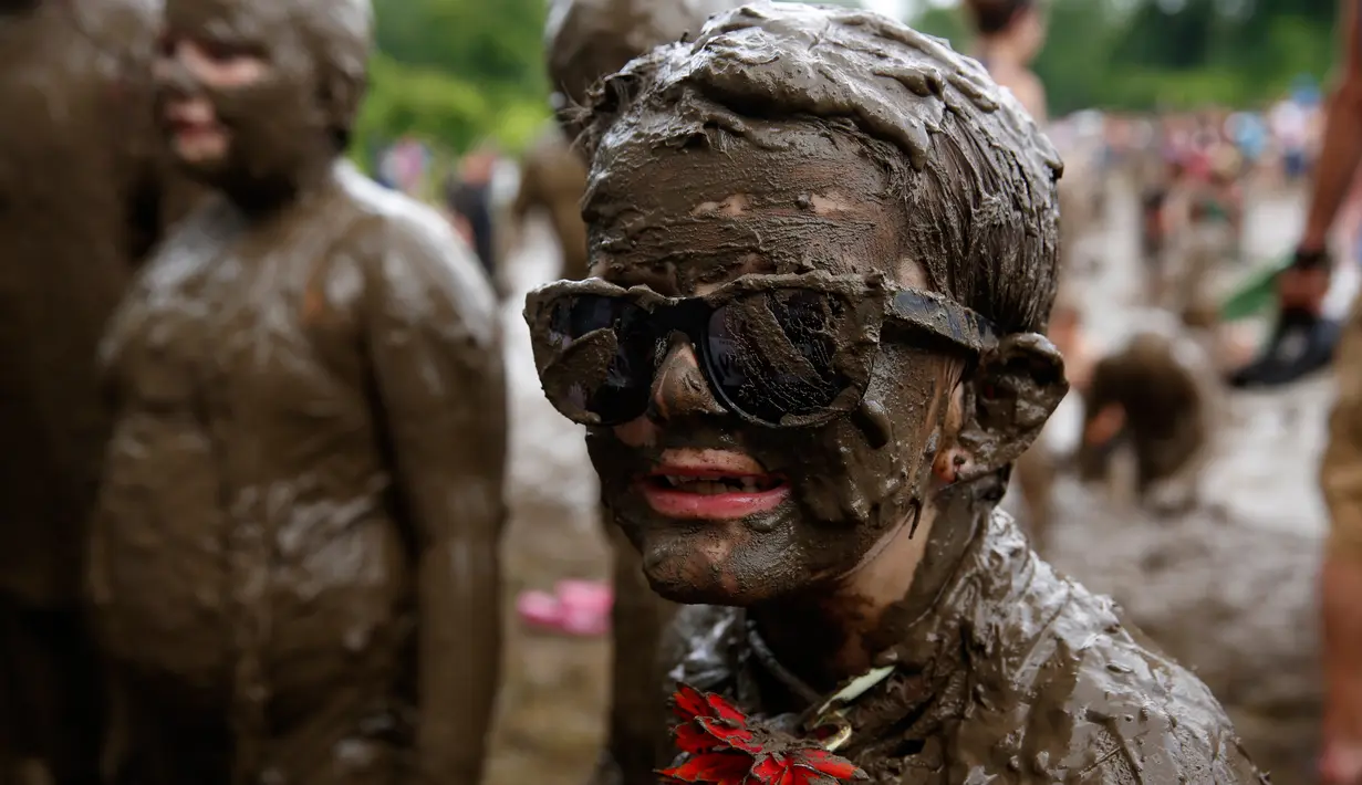 Seorang anak memakai kacamata hitam penuh lumpu saat ikut dalam perayaan Mud Day di Nankin Mills Park di Westland, Michigan, AS (11/7). Dalam lubang lumpur tersebut berisi 200 ton tanah yang sudah dicampur 75.708 liter air. (AFP Photo/Jeff Kowalsky)