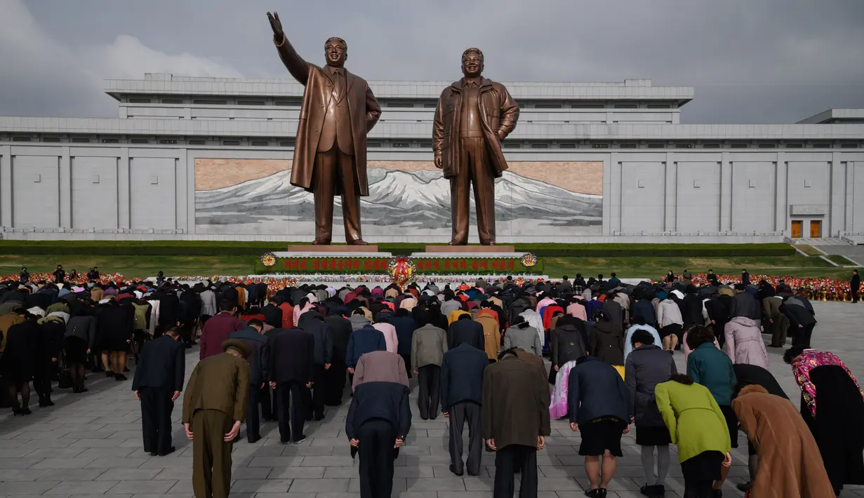 Orang-orang membungkuk ketika mereka memberi penghormatan kepada patung-patung pemimpin Korea Utara Kim Il Sung dan Kim Jong Il di Pyongyang (15/4). Mereka melakukan penghormatan untuk memperingati ulang tahun Kim Il Sung.  (AFP Photo/Ed Jones)