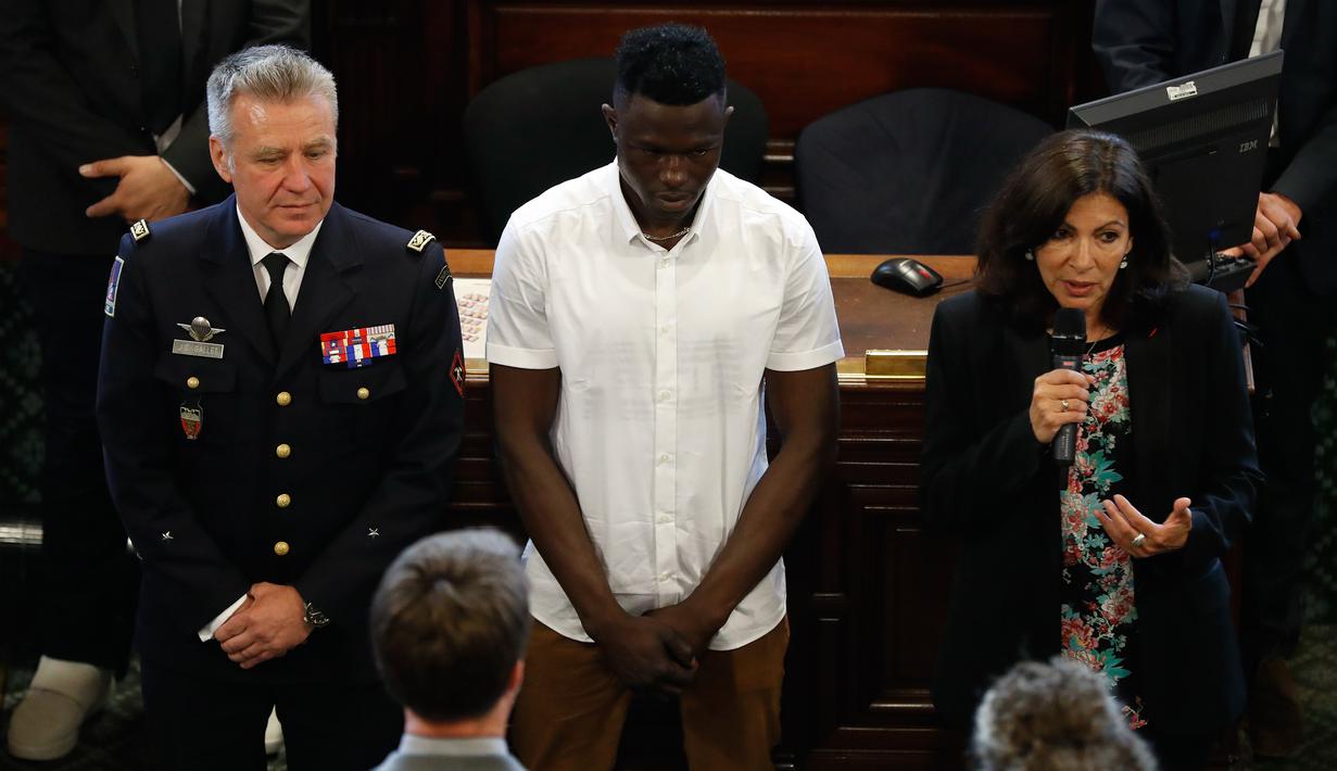 Walikota Paris Anne Hidalgo (kanan) memberi sambutan saat memberi penganugerahan kepada imigran Mali Mamoudou Gassama (tengah) di Paris, Prancis (4/6). (AFP/Francois Guillot)