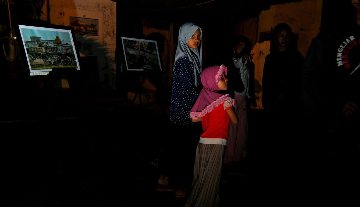 Sejumlah warga menghadiri upacara doa pada malam peringatan 17 tahun tsunami Boxing Day 2004 di monumen Kapal Tsunami Lampulo di Banda Aceh (25/12/2021). (AFP/Chaideer Mahyuddin)