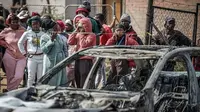 Warga berdiri di balik garis polisi di dekat lokasi penembakan di sebuah bar di Johannesburg, Afrika Selatan, Minggu (27/9/2026). (Dok. AFP)
