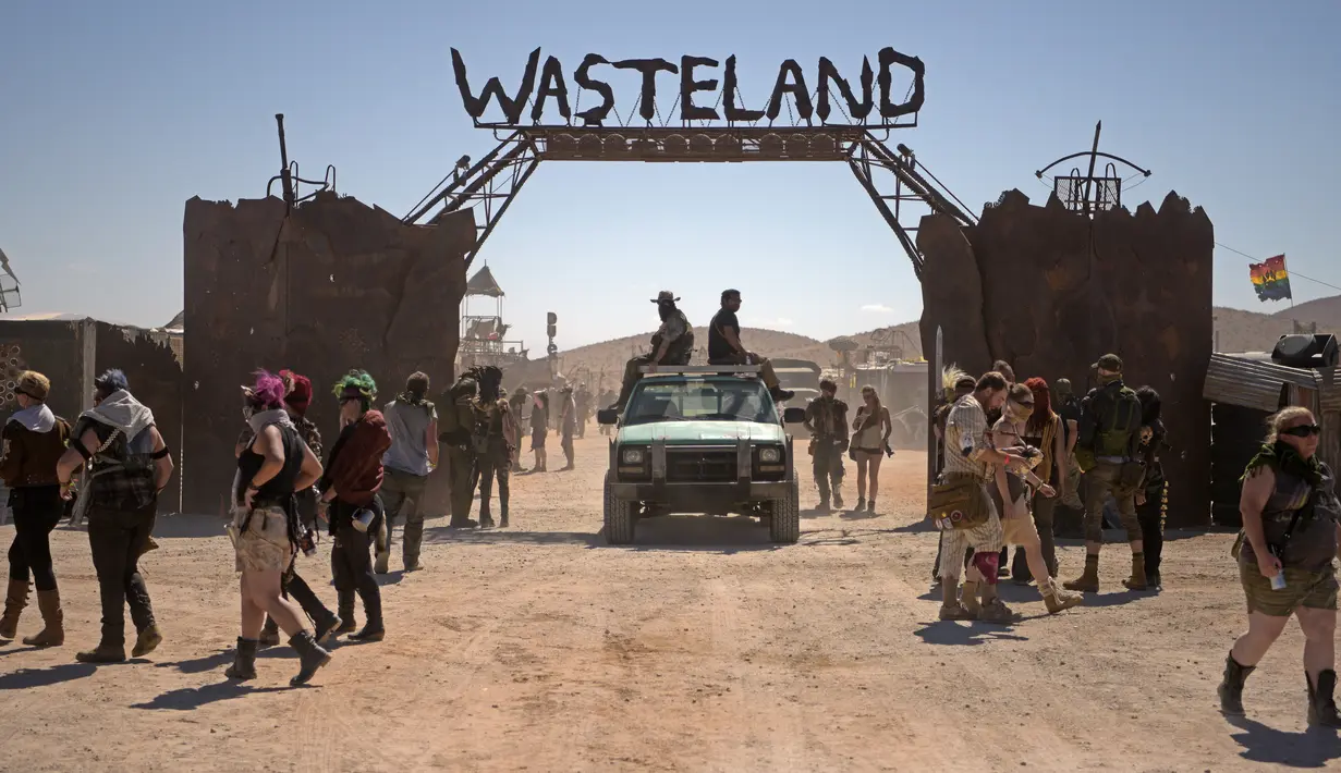 Para peserta berbaris di atas kendaraan ATV mereka dan berjalan di lapangan selama festival Wasteland Weekend di Gurun Mojave, North Edwards, California, AS, Sabtu (28/9/2019). (Agustin Paullier/AFP)
