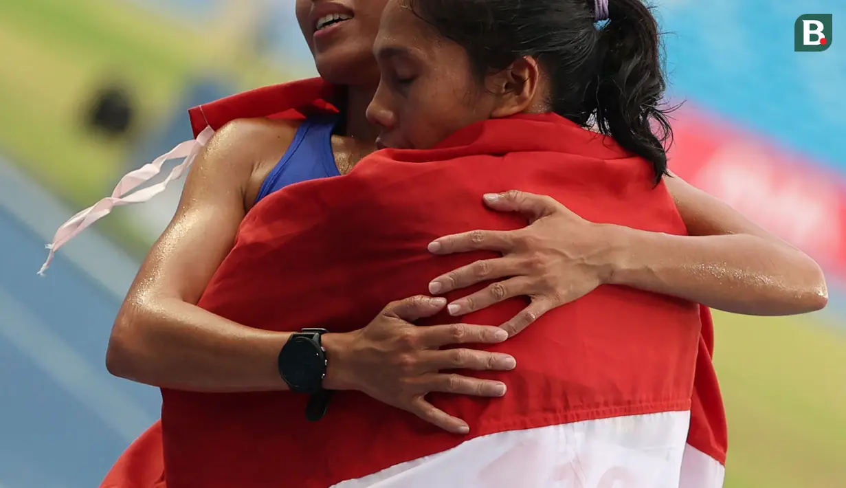 Pelari putri Indonesia, Odekta Elvina Naibaho dipeluk oleh pelari putri Filipina setelah menyelesaikan nomor lari 10.000 meter SEA Games 2023 di Stadion Morodok Techo National Stadium, Phnom Penh, Kamboja, Jumat (12/5/2023). Odekta meraih medali perunggu dengan catatan waktu 35 menit 31,03 detik sementara medali emas dan perak direbut dua atlet Vietnam, Thi Oanh Nguyen (35 menit 11,53 detik) dan Thi Hong Le Pham (35 menit 21,09 detik). (Bola.com/Abdul Aziz)