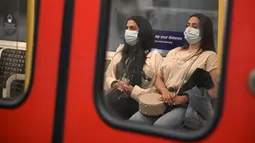 Para penumpang yang mengenakan masker menaiki kereta bawah tanah di pusat kota London, Senin (5/7/2021). PM Inggris Boris Johnson berencana mencabut sebagian besar pembatasan wilayah selama pandemi Covid-19, termasuk penggunaan masker dan jaga jarak mulai 19 Juli. (DANIEL LEAL-OLIVAS/AFP)