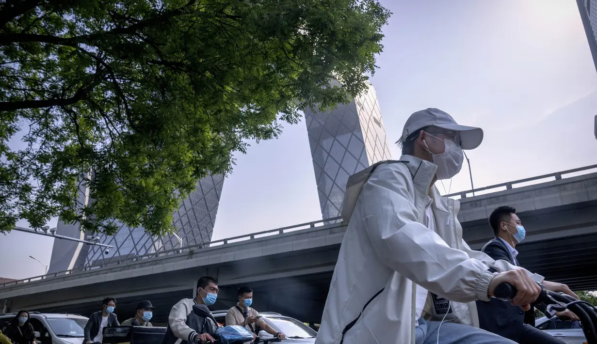 <p>Penumpang yang mengenakan masker menunggu di persimpangan di kawasan pusat bisnis di Beijing, Kamis (5/5/2022). Ibu kota China Beijing pada Kamis (5/5) mulai melonggarkan aturan karantina untuk kedatangan dari luar negeri. (AP Photo/Mark Schiefelbein)</p>