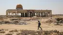 Seorang pria berjalan di depan terminal "Yasser Arafat International Airport" yang hancur dan sepi di Jalur Gaza, di kota Rafah, Palestina (24/6/2019). Bandara Yasser Arafat berdiri berkat Perjanjian Oslo II tahun 1995. (AFP Photo/Said Khatib)