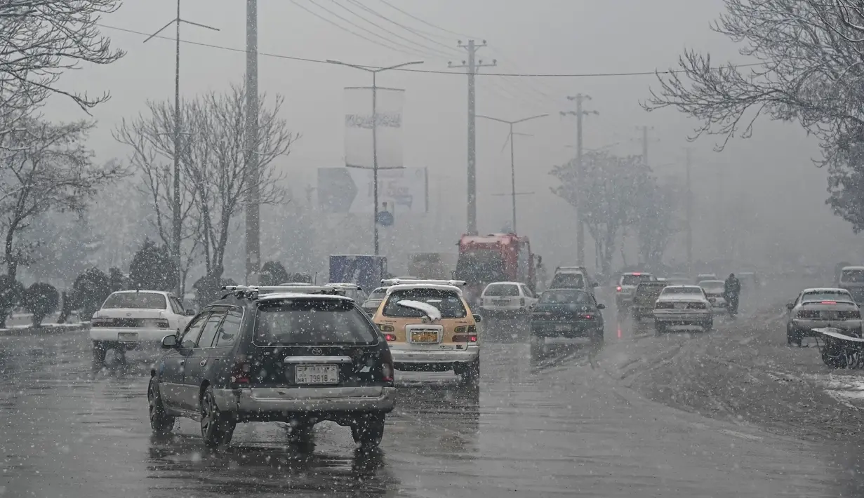 Komuter berjalan di sepanjang jalan saat hujan salju lebat di Kabul (4/1/2022). Beberapa kecelakaan terjadi pada Senin (3/1) di tengah kondisi lalu lintas yang kacau setelah hujan salju lebat. (AFP/Mohd Rasfan)