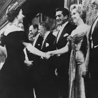 Ini adalah Marilyn Monroe di tahun 1956 saat ia bertemu dengan Ratu Elizabeth. Marilyn Monroe mengenakan strapless dress dengan sarung tangan panjang. Foto: Website.