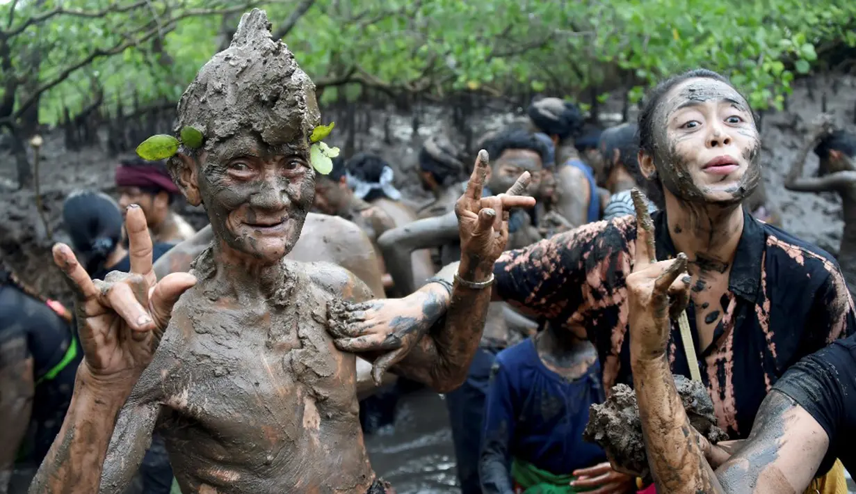 Orang-orang mengambil bagian dalam tradisi mandi lumpur yang dikenal sebagai Mebuug-buugan di Desa Kedonganan, Bali, 4 Maret 2022. Mebuug-buugan diadakan sehari setelah Nyepi yang bertujuan untuk menetralkan sifat buruk. (SONY TUMBELAKA/AFP)
