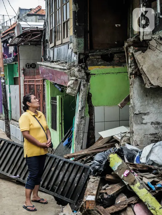 Warga melihat rumah yang roboh akibat pembuatan saluran air di Jalan Kayu Manis IX, Matraman, Jakarta Timur, Senin (16/12/2019). Pelaksana pembangunan saluran air akan bertanggung jawab memperbaiki rumah yang telah lapuk fondasinya tersebut mulai Senin. (Liputan6.com/Faizal Fanani)