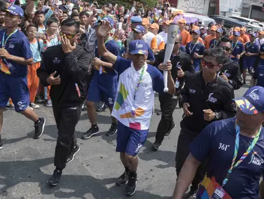 Pebalap sepeda legendaris Indonesia, Sutiyono, berlari saat mengikuti pawai obor Asian Games XVIII di Lampung, Rabu (8/8/2018). Sebanyak 53 kota di Indonesia akan dilalui oleh obor Asian Games. (Bola.com/Reza Bachtiar)