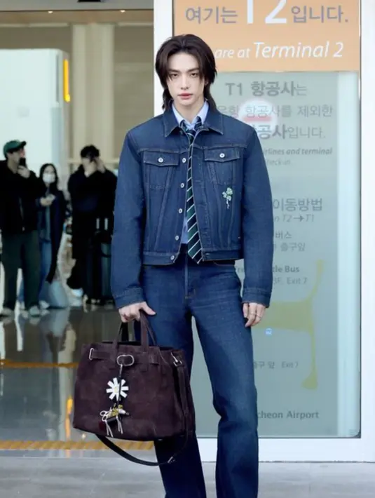 Melengkapi tampilannya dengan inner kemeja biru dipadukan dasi hijau bergaris yang memberikan kesan formal. Di tasnya ia menyematkan keyring bunga Daisy, kuda, dan lebah.  [Dok. Dior]