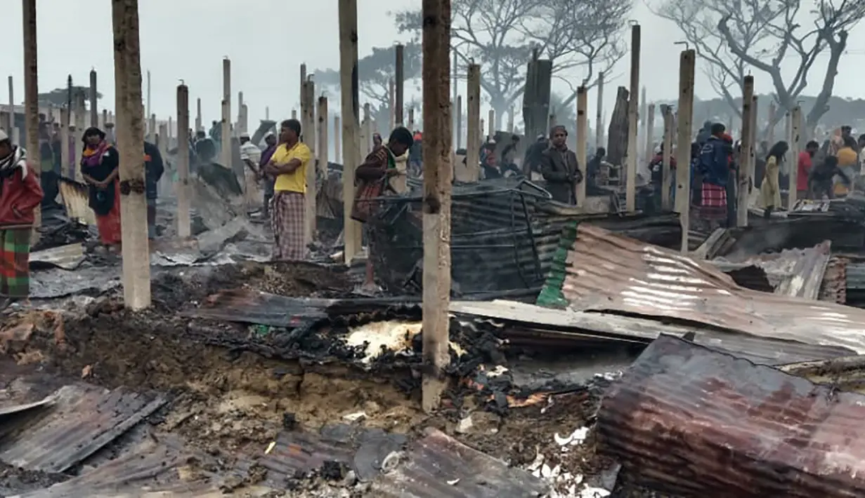 Pengungsi Rohingya berjalan di sisa-sisa yang hangus setelah kebakaran terjadi di Kamp Nayapara di distrik Cox's Bazar, Bangladesh, Kamis (14/1/2021). Ratusan rumah yang menjadi tempat tinggal ribuan pengungsi Rohingya hancur akibat dilalap api. (AP Photo/Mohammed Faisal)