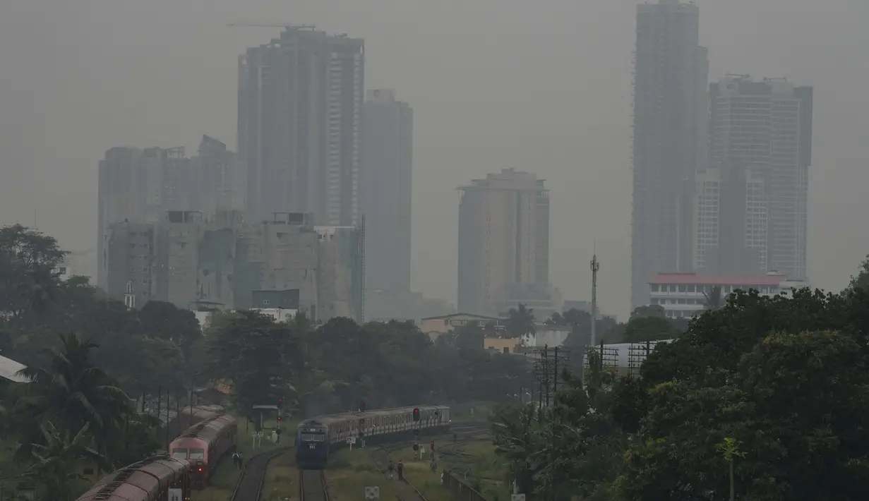 Sebuah kereta melintas saat kabut asap menyelimuti cakrawala di Kolombo, Sri Lanka, Jumat, 9 Desember 2022. Kondisi ini ditambah dengan badai di Teluk Benggala memicu hujan lebat dan angin kencang melintasi Sri Lanka dalam beberapa hari terakhir. (AP Photo/Eranga Jayawardena)