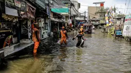 Petugas PPSU membersihkan sampah saat terjadi banjir rob di Pelabuhan Kali Adem, Muara Angke, Jakarta, Selasa (9/11/2021). Walau terendam banjir rob, petugas PPSU tetap sigap bersihkan sampah yang mengambang terbawa air laut. (Liputan6.com/Faizal Fanani)