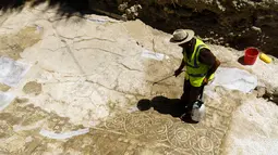 Seorang Arkeolog membersihkan pasir-pasir yang menutupi mosaik menggunakan air di Larnaca, Siprus (14/7).Mereka percaya bahwa mosaik ini merupakan peninggalan Romawi dari Kerajaan Kition. (Iakovos Hatzistavrou / AFP)