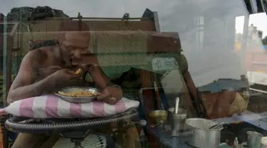 Seorang sopir makan di sebuah truk yang diparkir di terminal di Chennai (19/9/2019). Layanan transportasi darat menyerukan pemogokan satu hari untuk memprotes kenaikan pinalti di bawah Undang-undang Kendaraan Bermotor (Amandemen) yang baru. (AFP Photo/Arun Sankar)