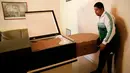 Seorang pria memasukkan peti mati karton ke dalam peti di kamar mayat di Valencia, negara bagian Carabobo, Venezuela, Kamis (25/08). Rakyat Venezuela kekurangan uang dan terpaksa mengubur mereka yang meninggal dalam kotak kardus. (REUTERS/Marco Bello).