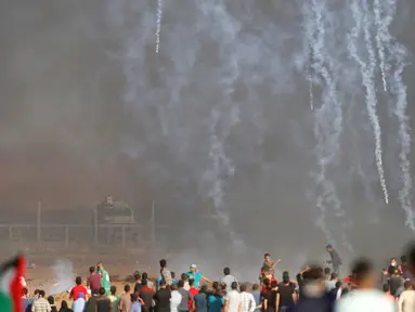 Pasukan Israel menembakkan gas air mata ke arah demonstran Palestina selama bentrokan di perbatasan jalur Gaza (11/5). Warga Palestina menggelar aski yang berujung bentrokan di perbatasan jalur Gaza. (AFP Photo/Mohammed Abed)