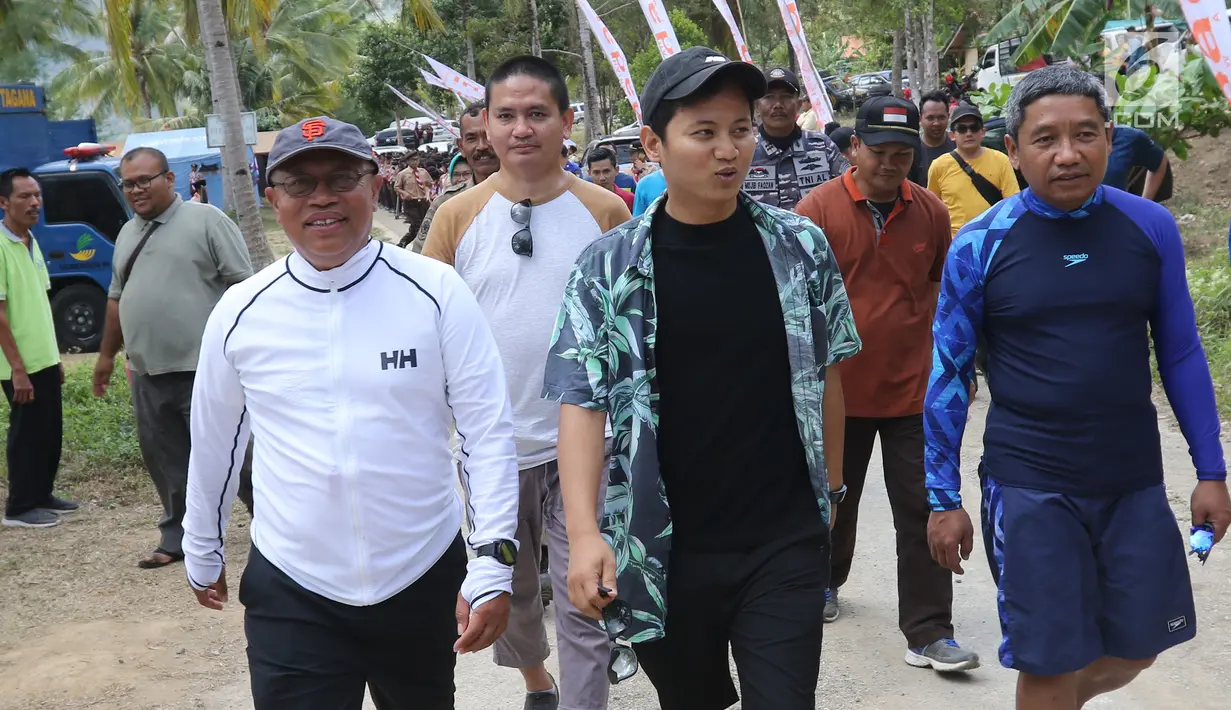 Dirut BPJS Ketenagakerjaan, Agus Susanto dan Bupati Trenggalek, Mochammad Nur Arifin berjalan di Pantai Mutiara, Trenggalek, Jawa Timur, Sabtu (7/9/2019). Bantuan 100 terumbu karang untuk meningkatkan pariwisata di Kabupaten Trenggalek agar ekonomi semakin meningkat. (Liputan6.com/Herman Zakharia)