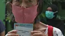 Warga lanjut usia (lansia) menunjukkan nomor antrean vaksinasi Covid-19 di Puskesmas Kecamatan Senen, Jakarta Pusat, Selasa (23/2/2021). aksinasi untuk Lansia akan dimulai di ibu kota provinsi untuk seluruh provinsi di Indonesia, di prioritaskan di Jawa-Bali. (Liputan6.com/Herman Zakharia)