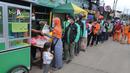 Warga mengantre untuk mendapatkan bubur gratis di kawasan  pintu keluar tol Kukusan Depok, Jawa Barat, Kamis (20/1/20222). Sudah hampir lima bulan ini, setiap pagi pukul 07.30  dibagikan sekitar 100 porsi bubur kepada warga. (merdeka.com/Arie Basuki)