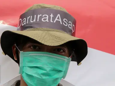 Massa dari Aksi Cepat Tanggap (ACT) melakukan aksi menolak asap dengan menggunakan masker di Patung Kuda, Jakarta, Senin (26/10). Aksi itu menuntut elemen masyarakat agar terlibat langsung dalam upaya penuntasan masalah asap. (Liputan6.com/Faizal Fanani)