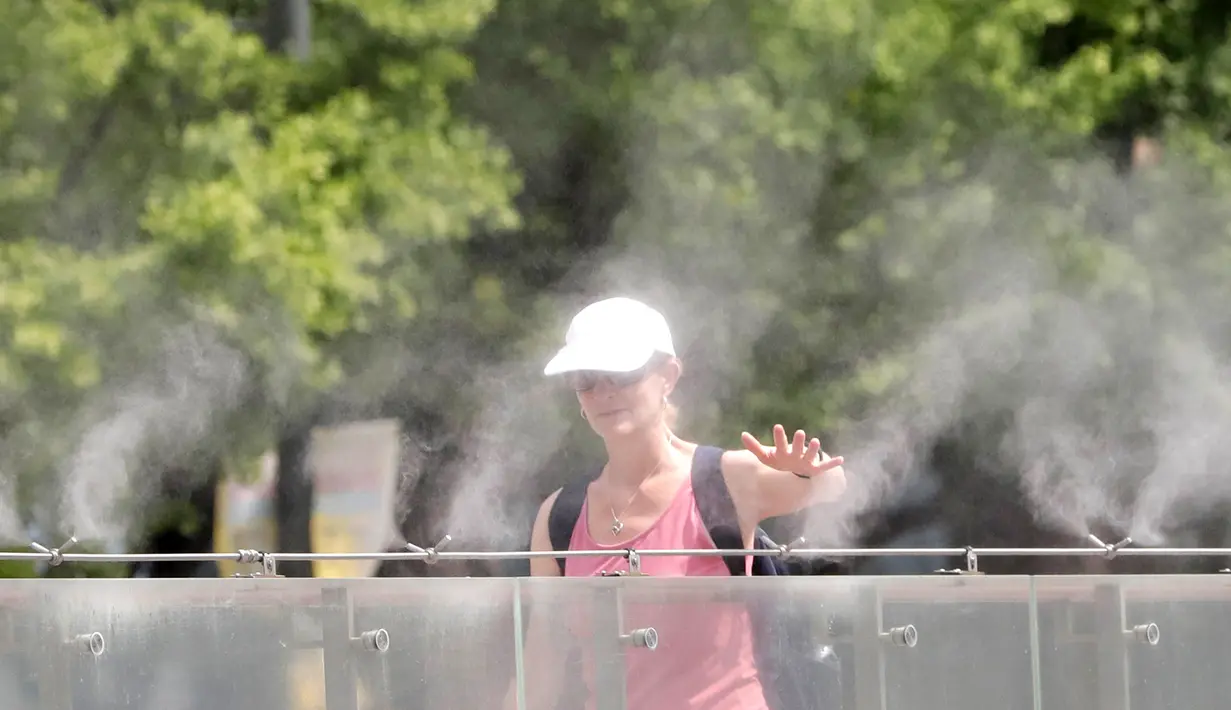Pengunjung berjalan melalui kabut air untuk mendinginkan diri di Lapangan Gwanghwamun, Seoul, Korea Selatan, Senin (23/7). (AP Photo/Lee Jin-man)