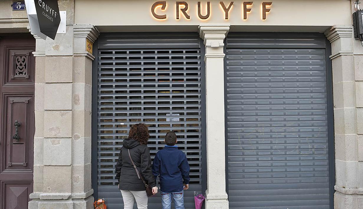 Pecinta sepak bola dunia berduka denagn meletakan bunga di depan Cruyff Store yang terdapat di Barcelona, Kamis (24/3/2016).  Bersama Ajax, Cruyff pernah meraih gelar Liga Champions sebanyak tiga kali. (AFP/Lluis Gene)