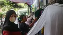 Kegiatan ini telah berlangsung selama sembilan tahun dan menjadi agenda rutin warga setiap Ramadan. Tampak dalam foto, warga memilih pakaian layak pakai yang dibagikan secara cuma-cuma di permukiman RT 02/RW 04 kawasan Jati Padang, Jakarta, Jumat (6/3/2026). (merdeka.com/Arie Basuki)
