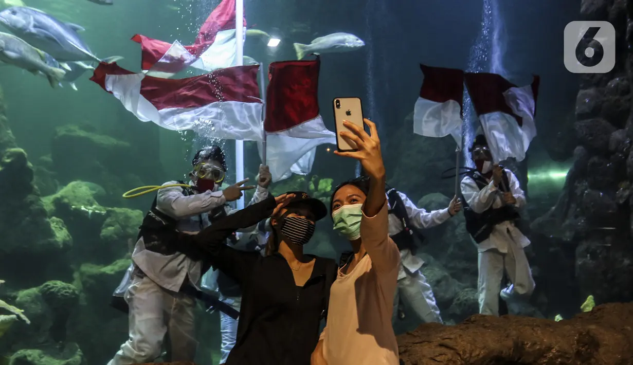 Penyelam mengibarkan bendera Merah Putih saat gladi resik HUT ke-75 RI dalam akuarium Sea World Ancol, Jakarta, Sabtu (15/8/2020). Taman Impian Jaya Ancol akan memperingati HUT ke-75 RI dengan mengibarkan bendera Merah Putih dalam akuarium Sea World pada 17 Agustus 2020. (Liputan6.com/Johan Tallo)