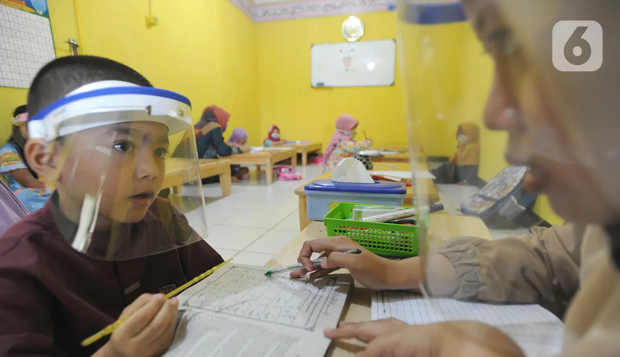 Murid menggunakan face shield belajar iqro di Taman Pendidikan Al-Qur'an (TPA) Al-Muthmainnah Cinere, Depok, Rabu (1/7/2020). Proses belajar mengajar dilakukan dengan protokol kesehatan dimana murid diwajibkan menggunakan masker atau face shield. (merdeka.com/Arie Basuki)