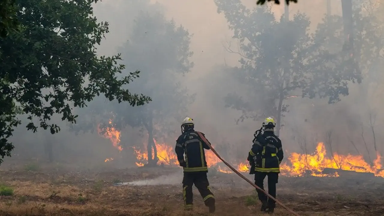 Petugas pemadam kebakaran menyemprotkan air ke hutan yang terbakar di wilayah Lège-Cap-Ferret, Prancis barat, Jumat (24/7/2026).