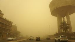 Kendaraan melaju di jalan di ibu kota Irak, saat debu tebal akibat badai pasir menyelimuti kota itu, pada Senin (23/5/2022). Irak menutup bandara dan gedung-gedung publik saat badai pasir -- yang kesembilan sejak pertengahan April -- melanda negara itu, kata pihak berwenang. (Sabah ARAR / AFP)