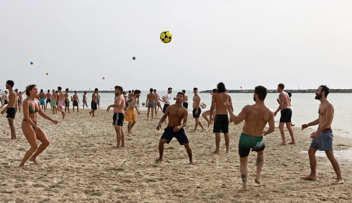Orang-orang bermain sepak bola di pantai di kota pesisir Israel Tel Aviv (19/4/2021). Dengan lebih dari setengah populasi divaksinasi penuh dalam salah satu kampanye inokulasi COVID-19 tercepat di dunia. (AFP/menahem kahana)