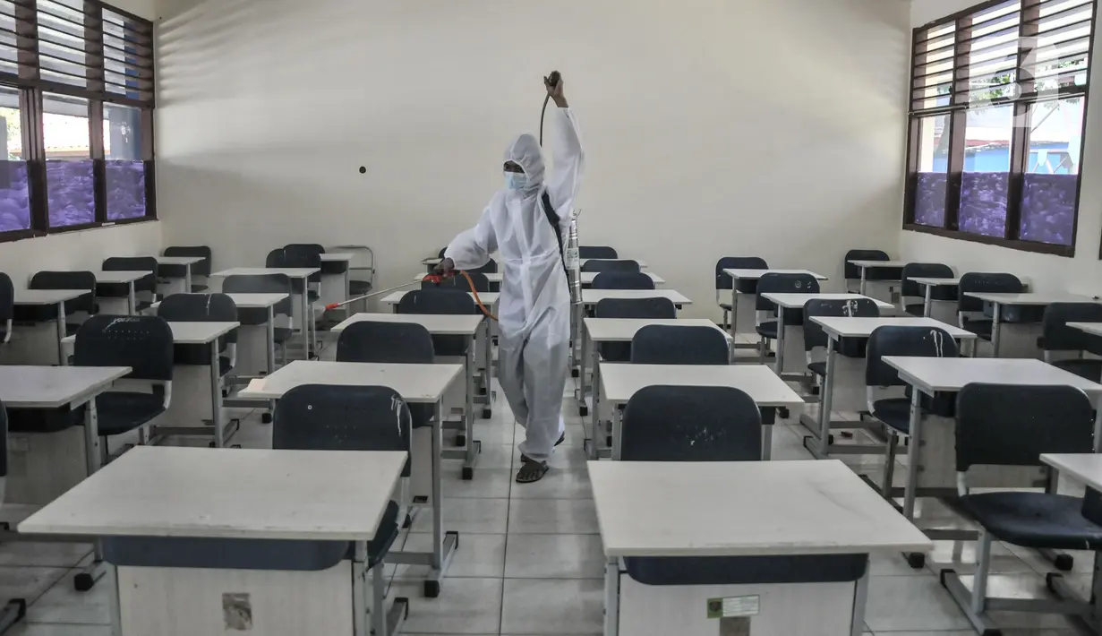Petugas sekolah menyemprotkan disinfektan di salah satu ruang kelas usai Pembelajaran Tatap Muka (PTM) 100 persen di SMP Negeri 9 Depok, Senin (24/1/2022). Penyemprotan disinfektan juga guna mengantisipasi penyebaran Covid-19 varian Omicron yang terus meningkat. (merdeka.com/Iqbal S Nugroho)
