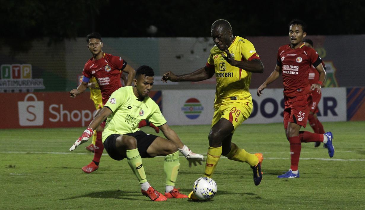 Striker Bhayangkara FC, Herman Dzumafo, berusaha melewati kiper Semen Padang, Teja Paku Alam, pada laga Shopee Liga 1 di Stadion PTIK, Jakarta, Sabtu (2/11). Bhayangkara bermain imbang 2-2 atas Semen Padang. (Bola.com/Yoppy Renato)