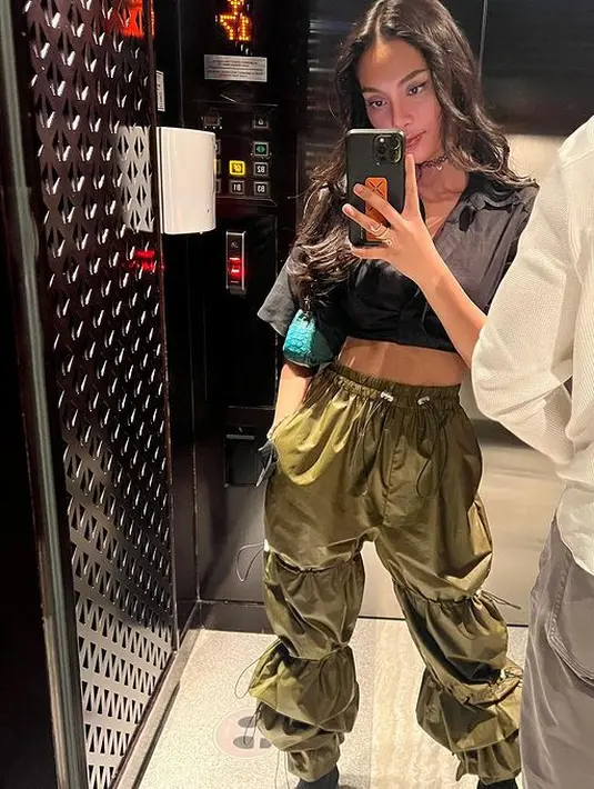 Meski tampil kasual, pesona Erika Carlina sebagai cewek mamba tetap terpancar. Memadukan kemeja crop top berwarna hitam dengan leather pants berwarna army yang membuatnya tampil chic.(instagram/eri.carl)