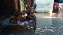 Seorang pria dan anak laki-laki makan di atas bangku saat banjir melanda daerah perumahan dekat tepi Sungai Yamuna yang meluap di New Delhi, India, Selasa (20/8/2019). (AFP Photo/Sajjad Hussain)