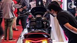 Pengunjung memperhatikan sepeda motor listrik yang dipamerkan pada pembukaan Indonesia Motorcycle Show (IMOS) 2022 di Jakarta Convention Center (JCC), Jakarta, Rabu (2/11/2022). Pameran ini diikuti oleh 25 merek, di antaranya 14 merek sepeda motor listrik. (Liputan6.com/Johan Tallo)