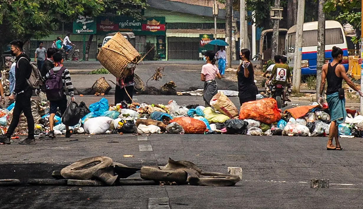 Seorang pengunjuk rasa membuang sampah di jalan saat demonstrasi menentang kudeta militer di kota Thaketa Yangon, Myanmar, Selasa (30/3/2021). "Serangan sampah" menjadi taktik baru untuk melawan junta militer saat jumlah korban tewas dalam demo anti-kudeta mencapai lebih dari 500. (HO/FACEBOOK/AFP)